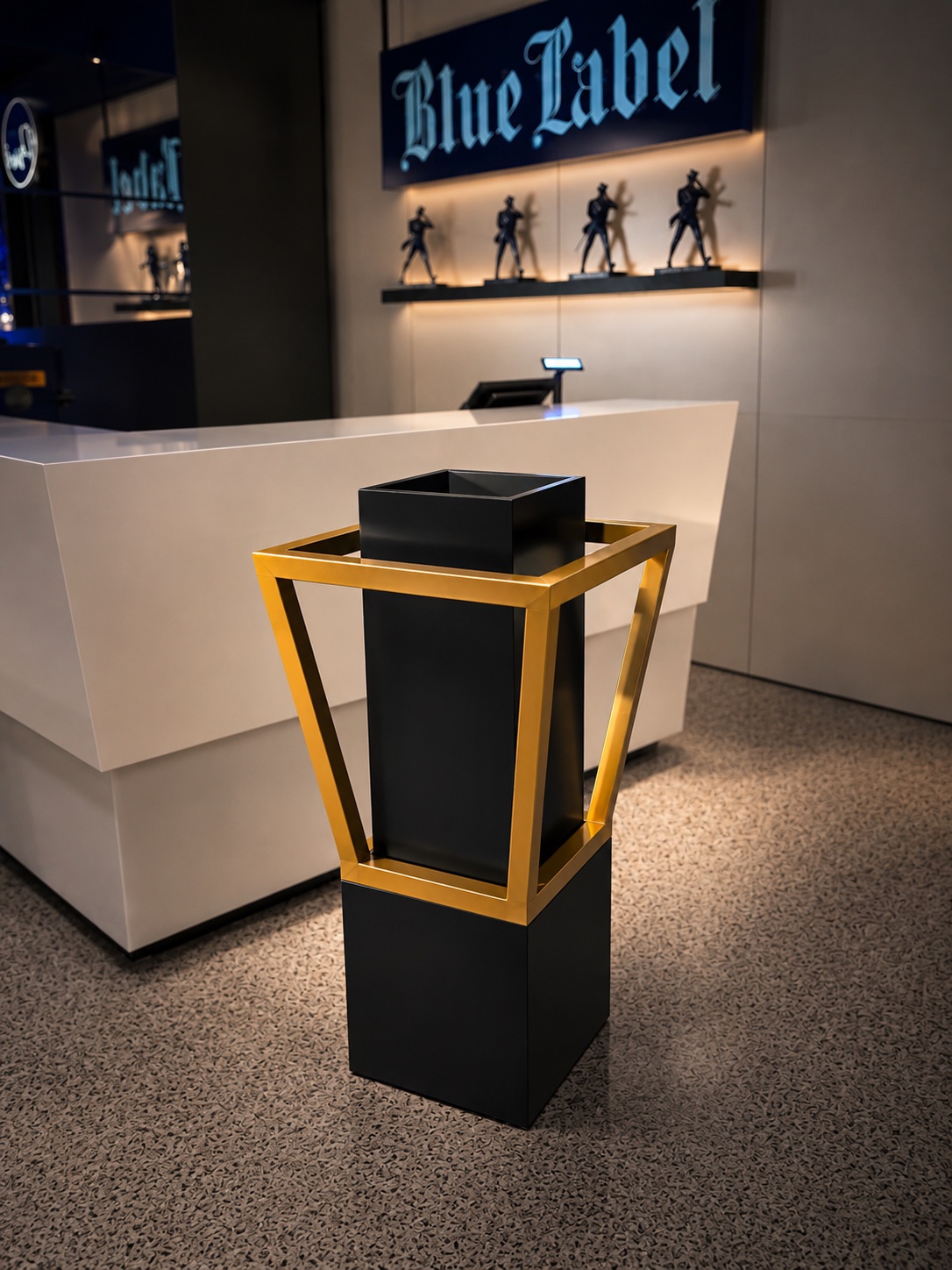 Black display pedestal with a gold-tone metal frame in the Blue Label interior