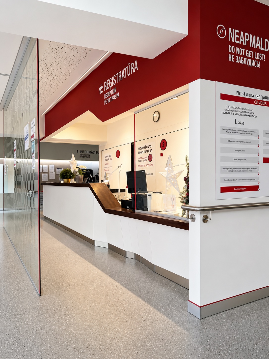 Clinic reception with red wayfinding signage and a white counter